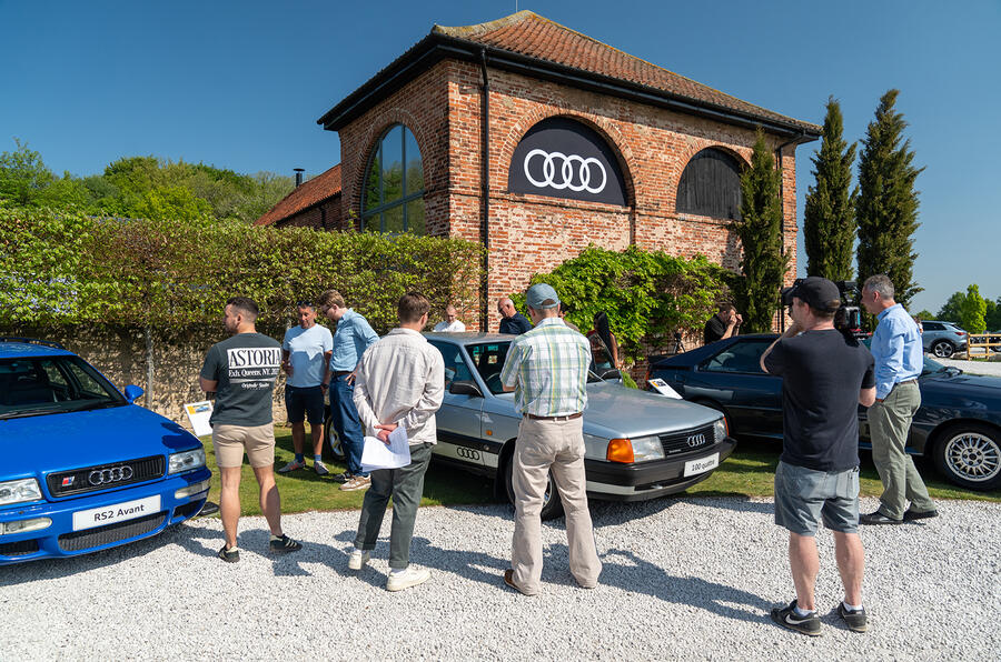 A man wearing shorts and shoes standing next to a car.
