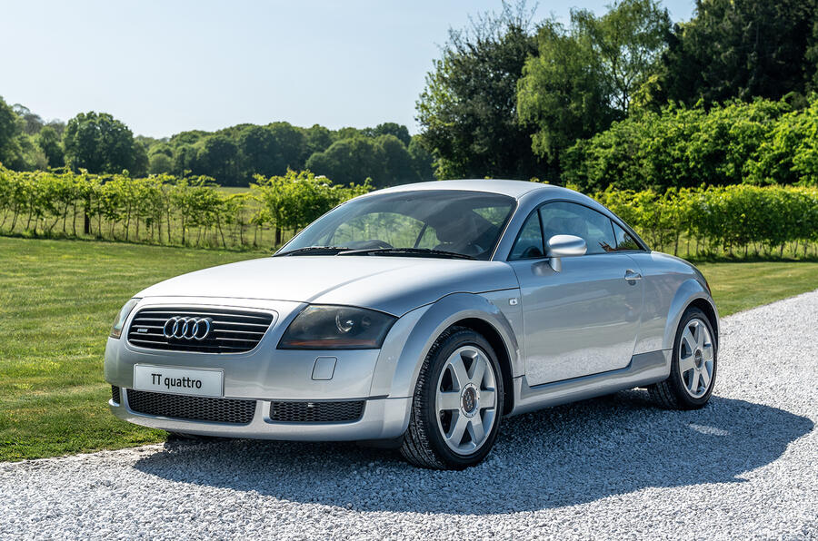 A silver sedan with alloy wheels parked on a city street.