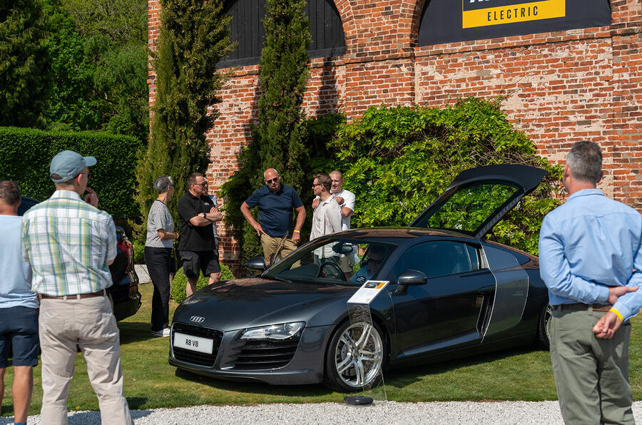 A man wearing shorts is standing next to a car, featuring alloy wheels with visible spokes and tires.