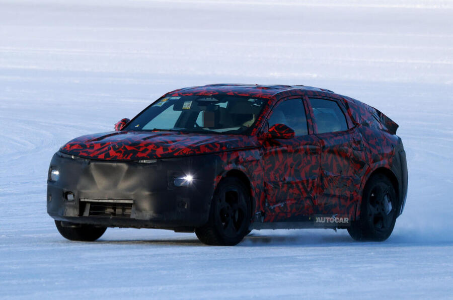 A modern red car parked on a city street, showcasing its sleek design and shiny wheels.