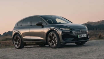 A sleek red car parked on a city street, showcasing its modern design and shiny wheels.
